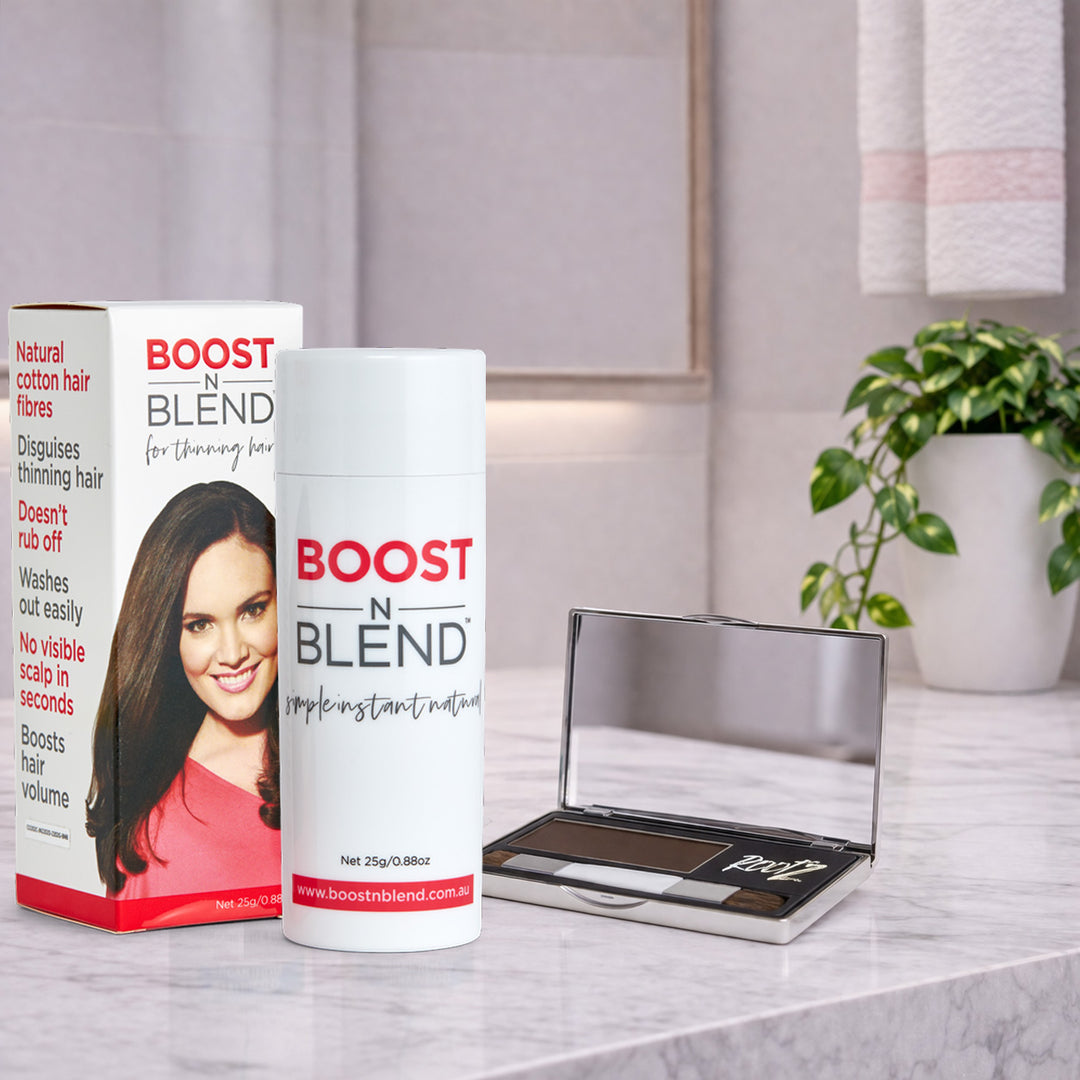 Boost N Blend hair fibres and Rootz hair concealer on a marble surface with a plant in the background