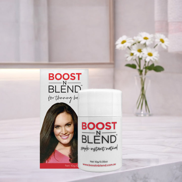 Boost N Blend hair fibres 10g on a bathroom counter with flowers in the background