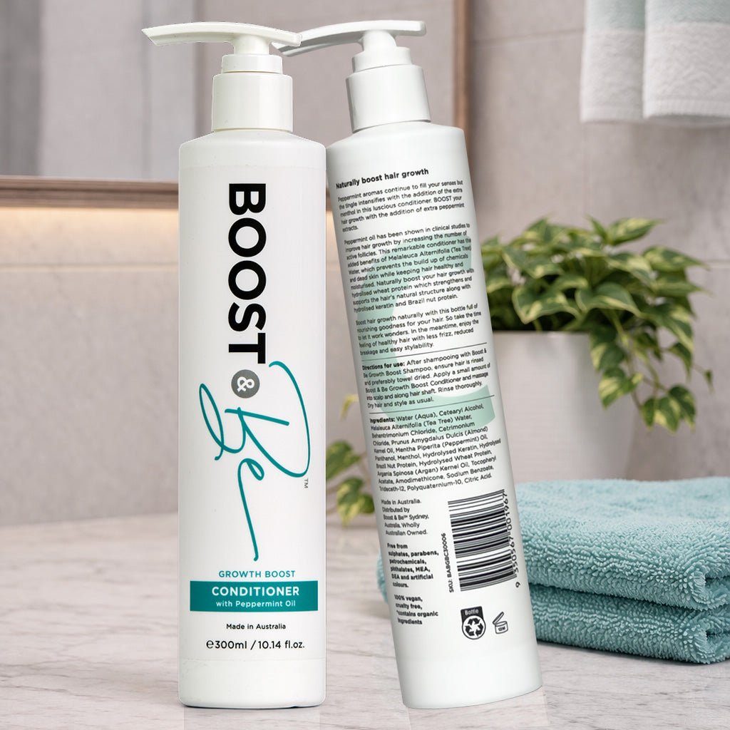 Boost & Be Growth Boost conditioner on a bathroom counter with a plant and towel in the background.