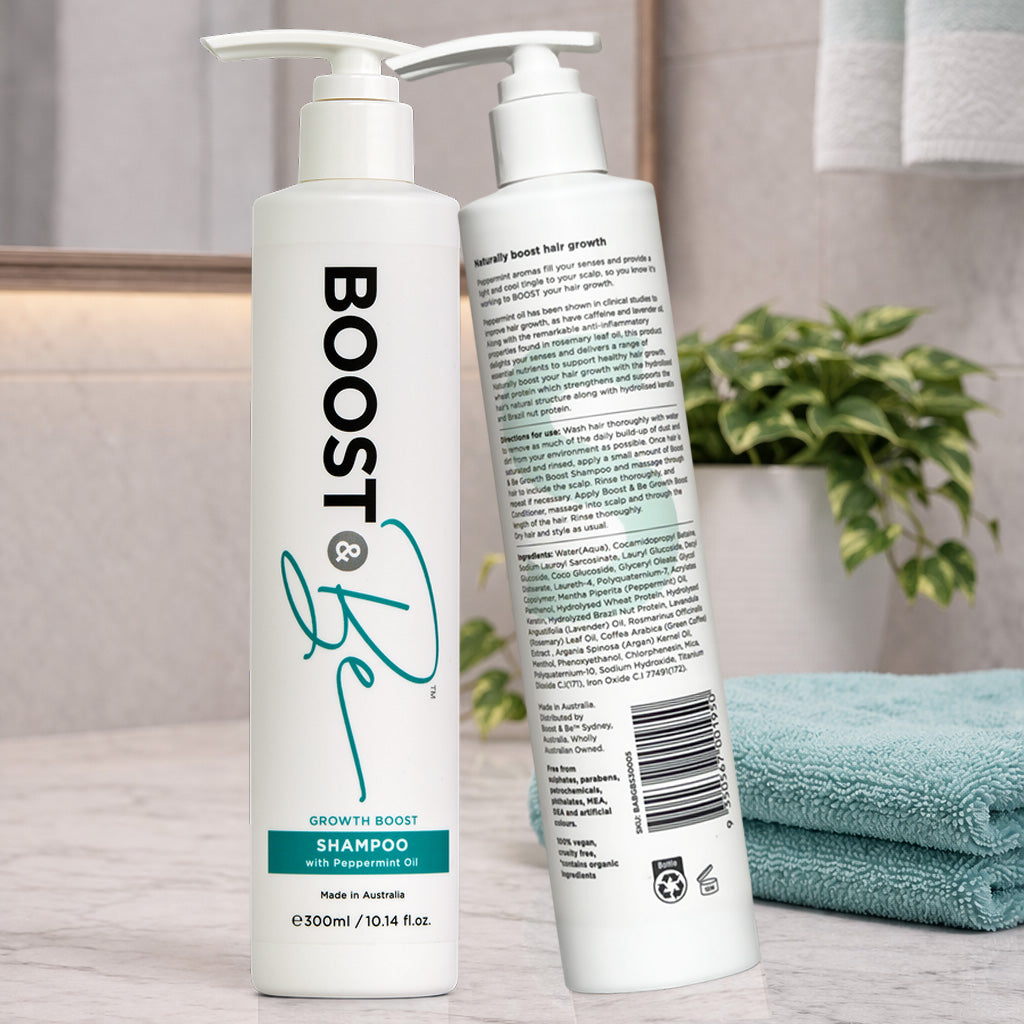Boost & Be Growth Boost shampoo on a bathroom counter with a plant and towel in the background.