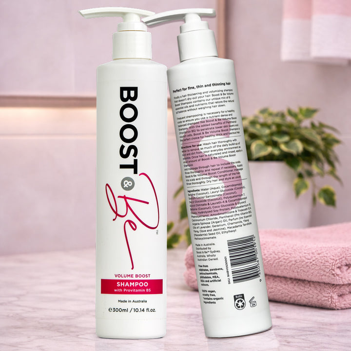 Boost & Be Volume Boost shampoo on a pink surface with a plant and towel in the background.