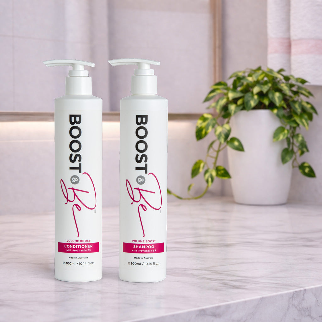 Boost & Be Volume Boost shampoo and conditioner on a marble surface with a plant in the background.