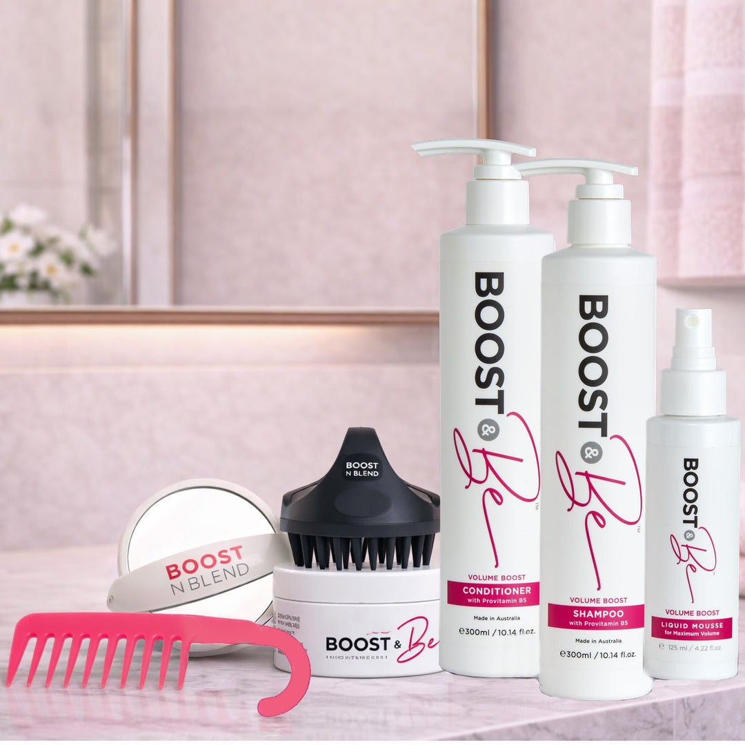 Boost & Be Volume Boost hair care products including shampoo, conditioner, and styling tools on a pink surface.